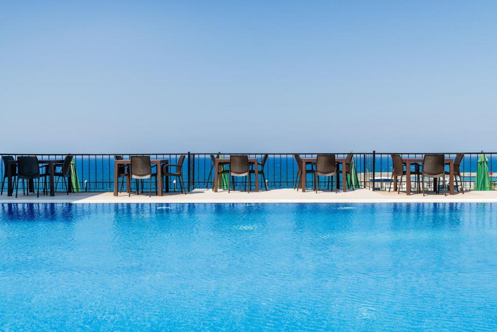 a swimming pool with chairs and blue water at Olivia Palm Hotel in Kyrenia