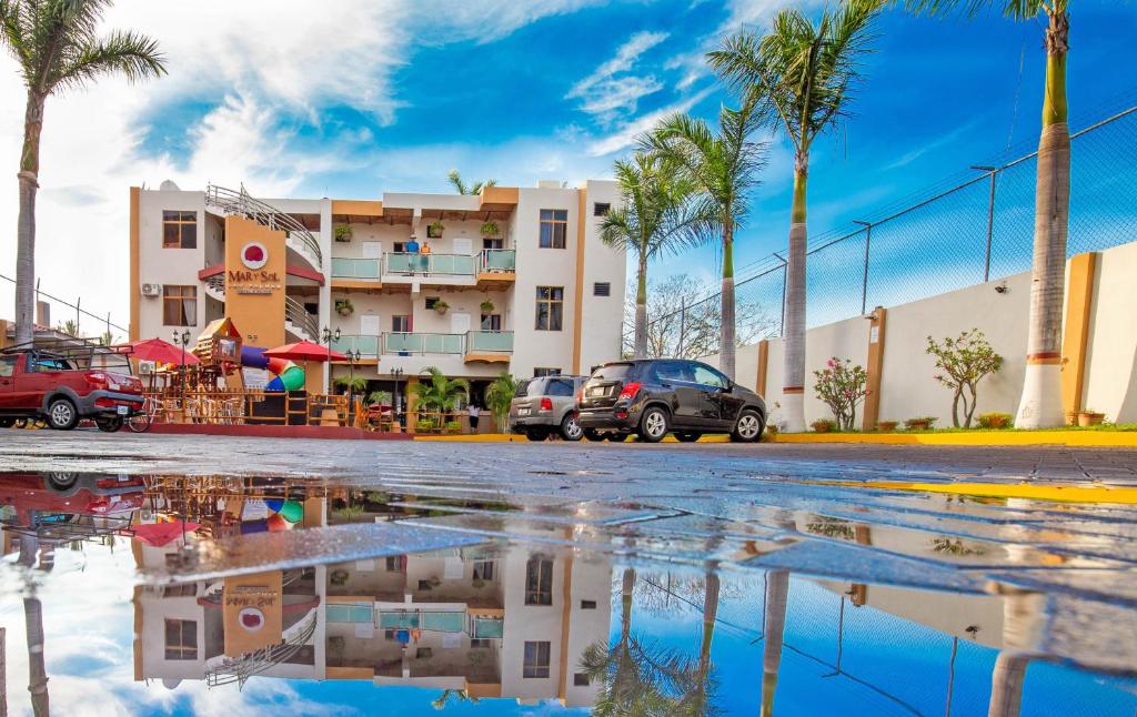 un charco de agua frente a un edificio con palmeras en Hotel & Suites Mar y Sol Las Palmas, en Rincón de Guayabitos
