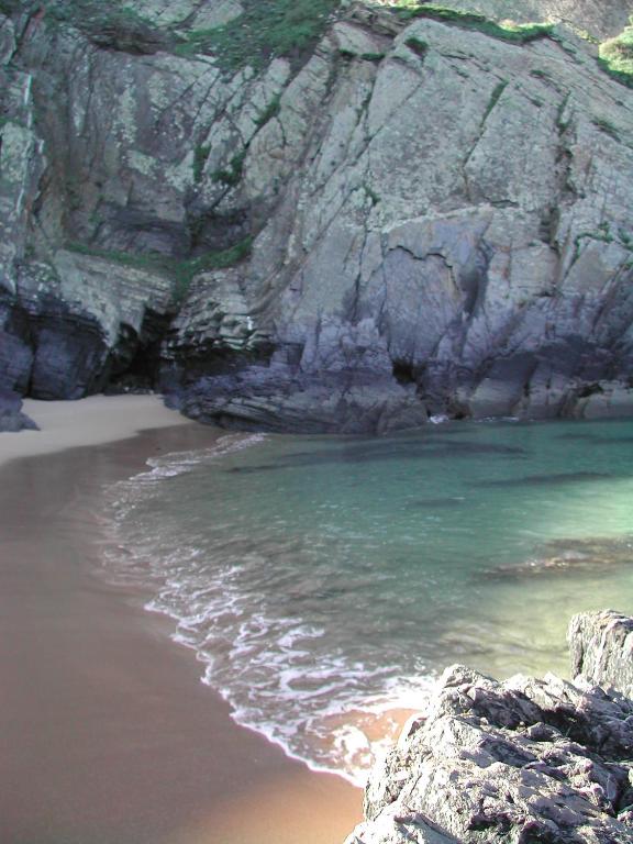 a beach with some rocks and the water at Bohemian Antique Guesthouse in Odeceixe