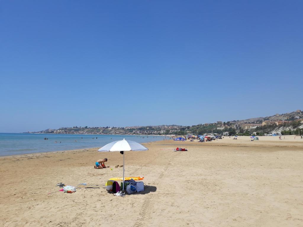 una spiaggia con ombrellone e persone in spiaggia di Vacanzasicilia a Porto Empedocle