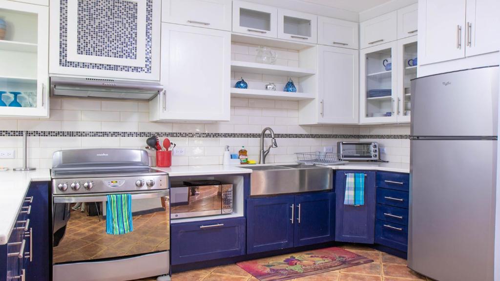 La cuisine est équipée de placards bleus et d'un réfrigérateur en acier inoxydable. dans l'établissement Ocotal Beach Front Condo #11, à Ocotal