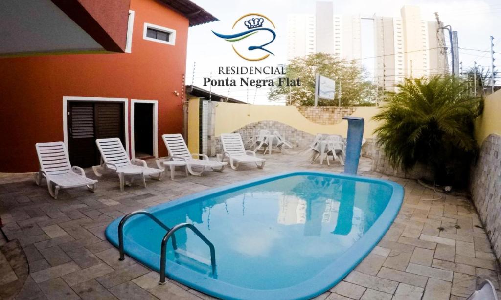 einem Pool vor einem Gebäude mit Stühlen in der Unterkunft Residencial Ponta Negra Flat in Natal