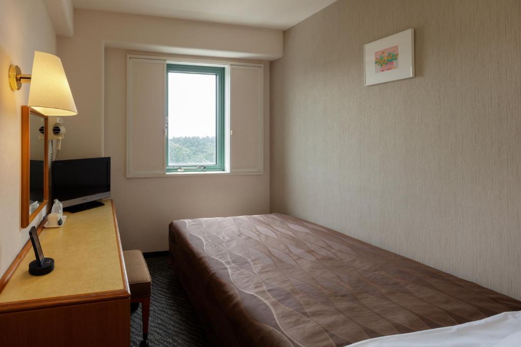 a hotel room with a bed and a window at Center Hotel Narita1 in Narita