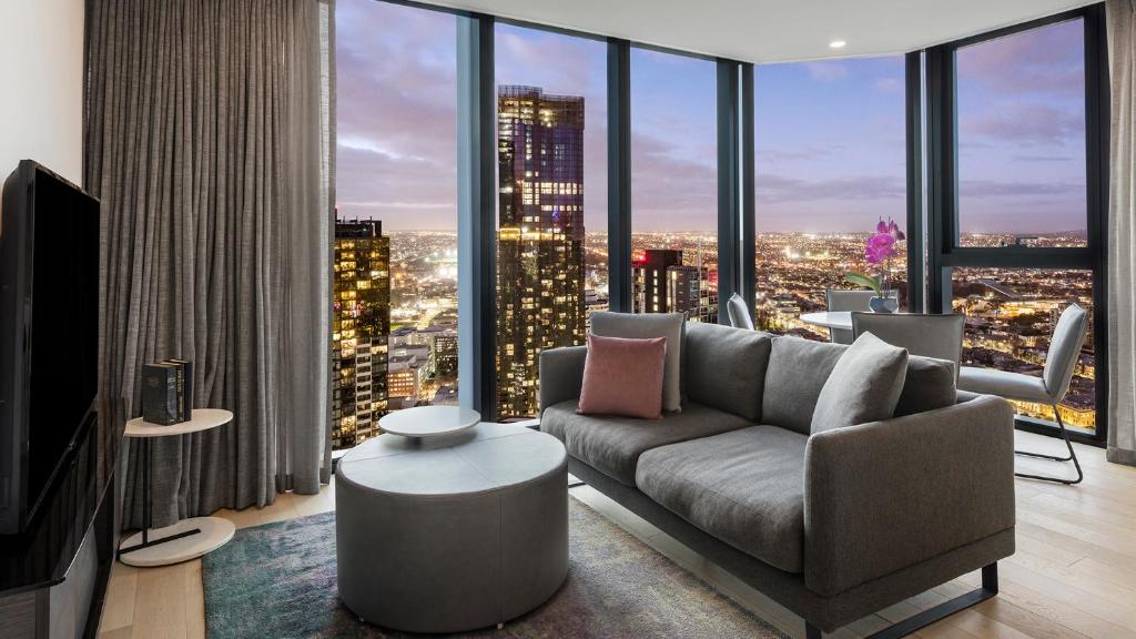 a living room with a couch and a large window at Avani Melbourne Central Residences in Melbourne