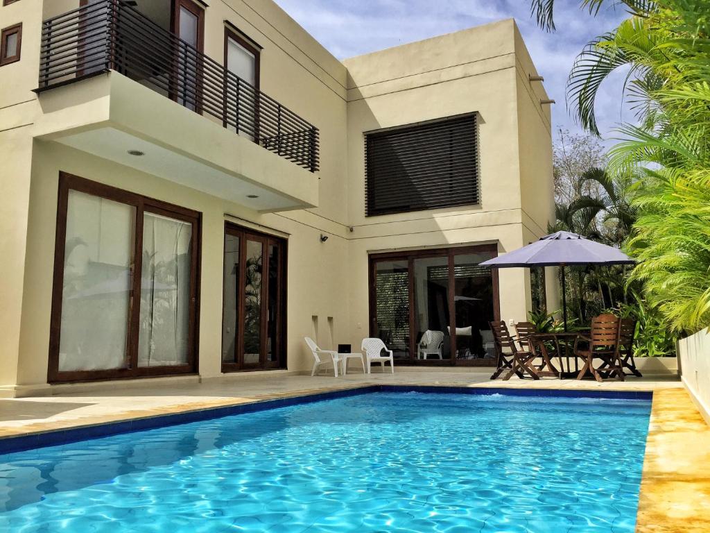 a villa with a swimming pool in front of a house at Lagos del Peñon: Casa 10 - Puerto Madero in Girardot