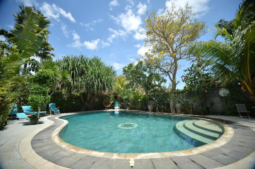 a large swimming pool in a yard with trees at Hibiscus House Pemuteran Bali in Pemuteran