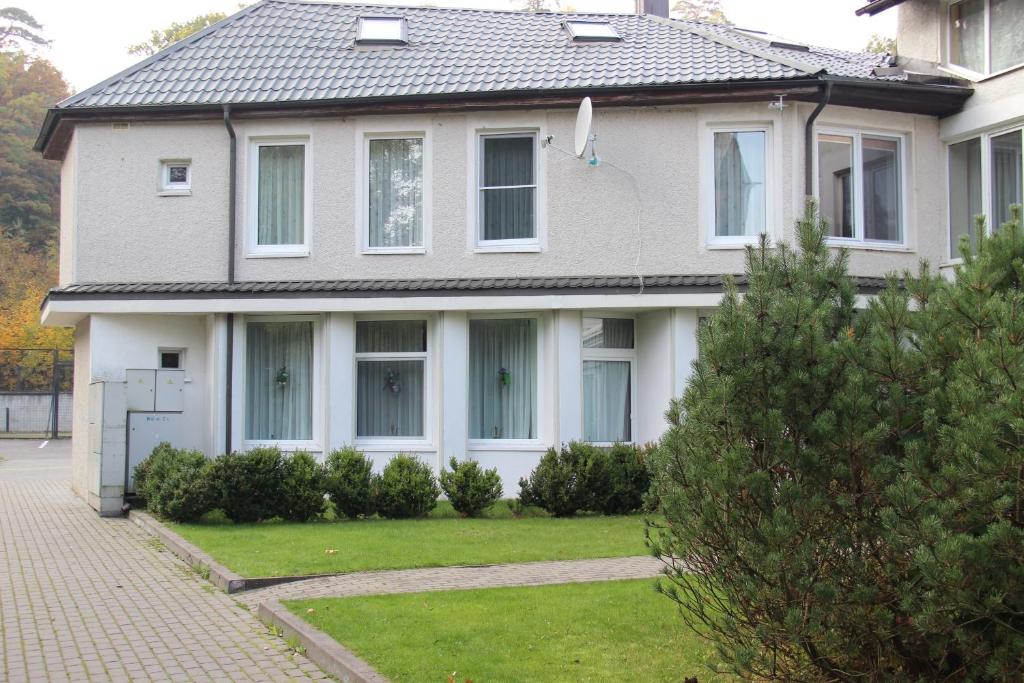 a white house with a grass yard in front of it at Rėzos Apartments in Juodkrantė