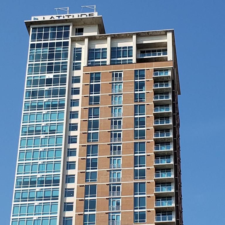 Hotel Latitude Med Center, a tall building with a sign on top of it at Latitude Med Center in Houston