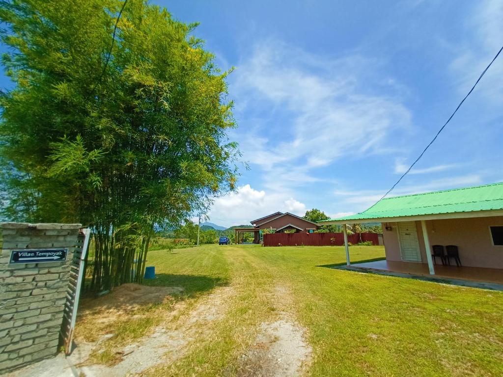 Un camino de tierra frente a una casa con un árbol. en villa tempoyak homestay, en Pantai Cenang