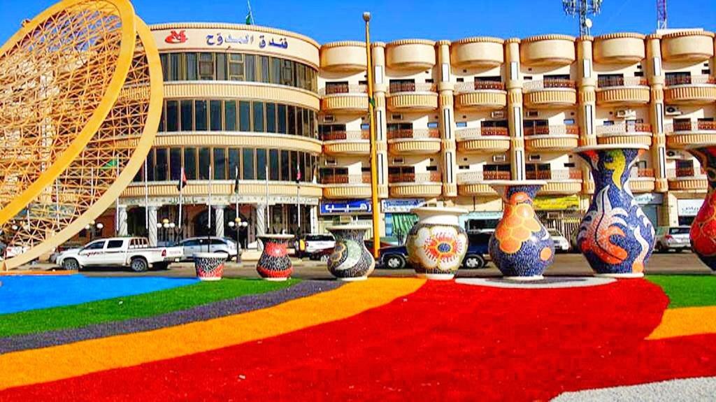 a large building with a lot of vases in front of it at Almudawah Hotel in Ţurayf