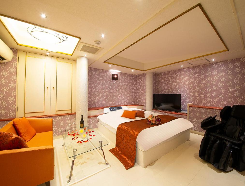 ein Schlafzimmer mit einem Bett, einem Sofa und einem TV in der Unterkunft Hotel Gee (Adult Only) in Sakai