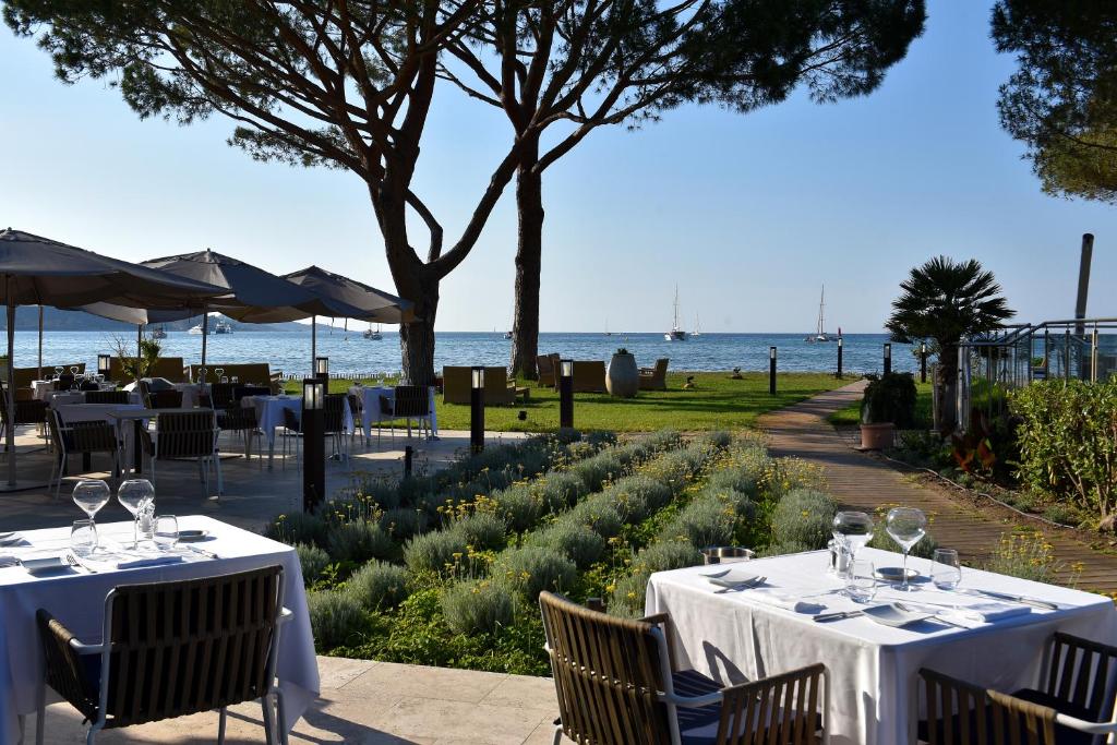 a restaurant with tables and chairs with a view of the ocean at Hôtel La Roya in Saint-Florent