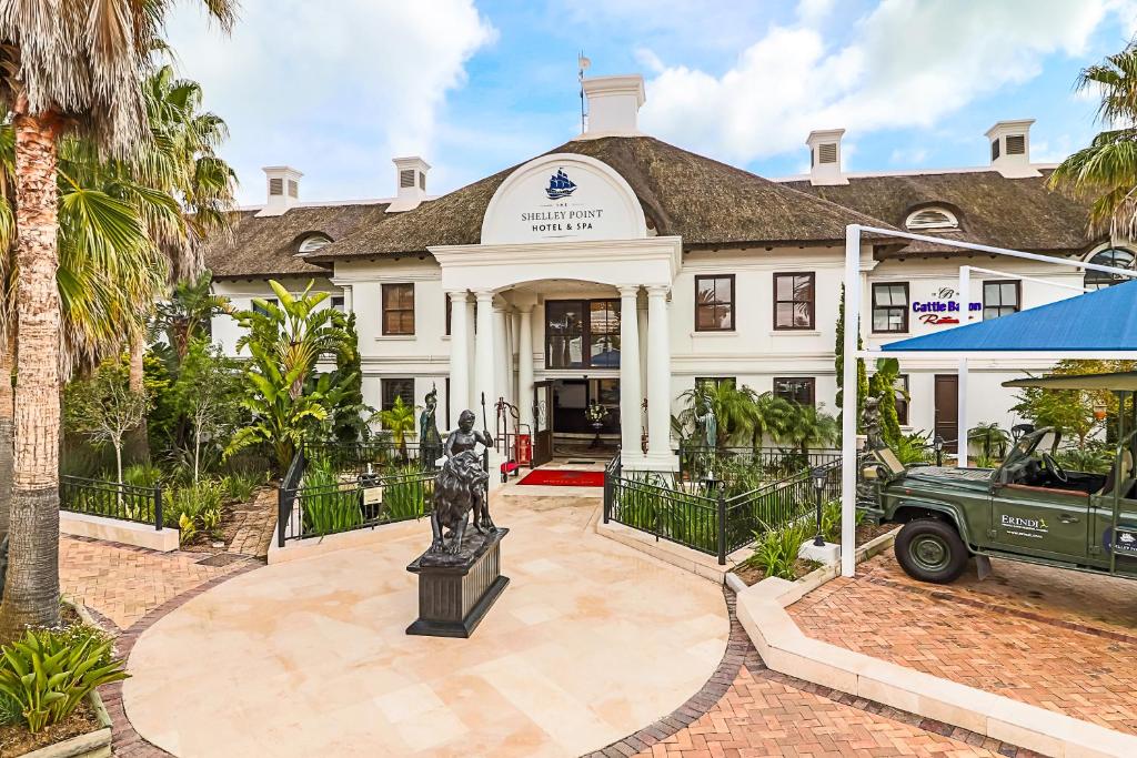 a large white house with a statue in front of it at The Shelley Point Hotel & Spa in St Helena Bay