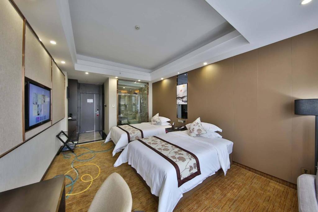 um quarto de hotel com três camas e uma televisão de ecrã plano em Ramada by Wyndham Zhangjiajie em Zhangjiajie