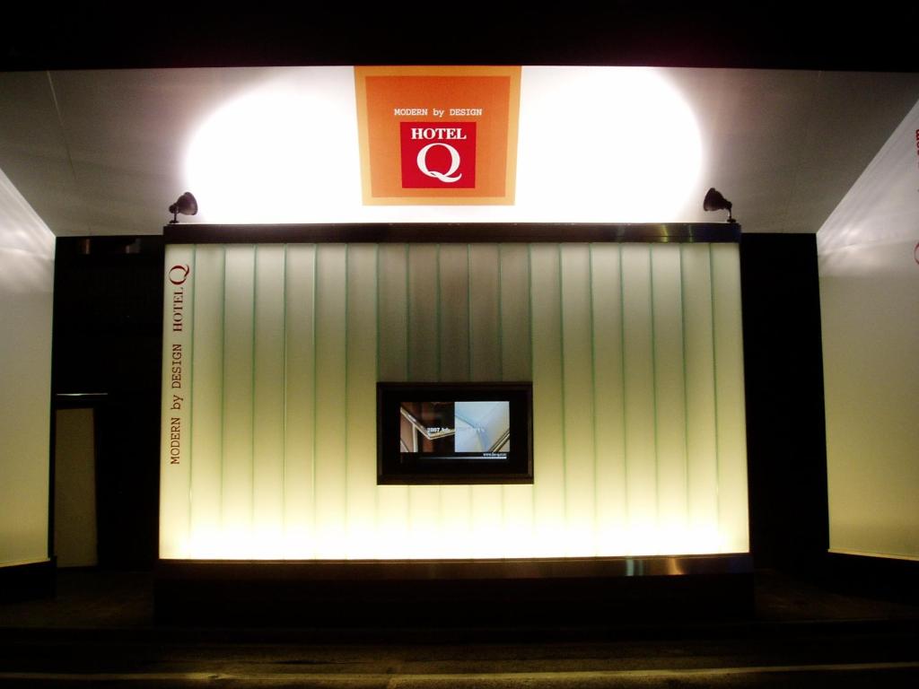 una stanza con un muro bianco con un cartello sopra di HOTEL Q a Tokyo