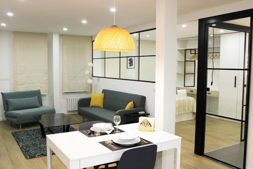 1 dormitorio y sala de estar con mesa y sillas. en Apartamenticos Plaza Sas I, en Zaragoza