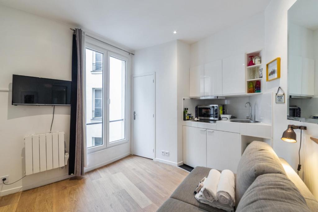 a living room with a couch and a kitchen at Cosy studio in Paris close to Grands Boulevards and Bourse - Welkeys in Paris