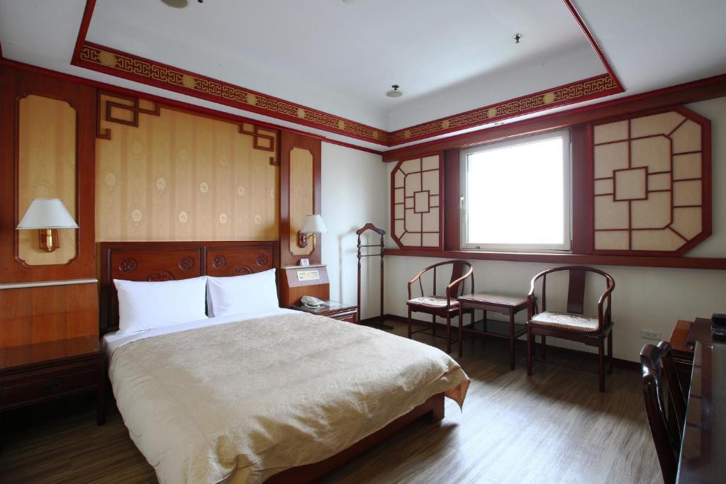 a bedroom with a bed and a table and chairs at Hua Du Hotel in Keelung