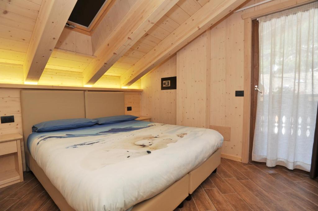 un grande letto in una camera con soffitto in legno di Casa Viola a Valdidentro