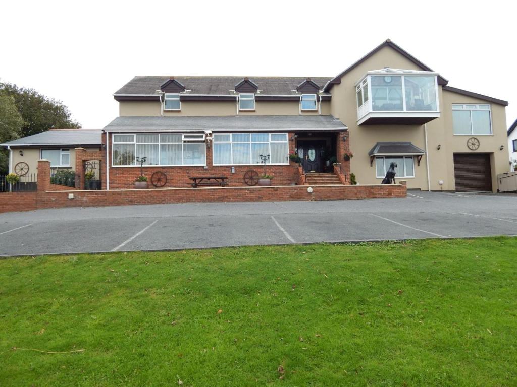 a house with a parking lot in front of it at Lakeland Guest House in Pembroke Dock