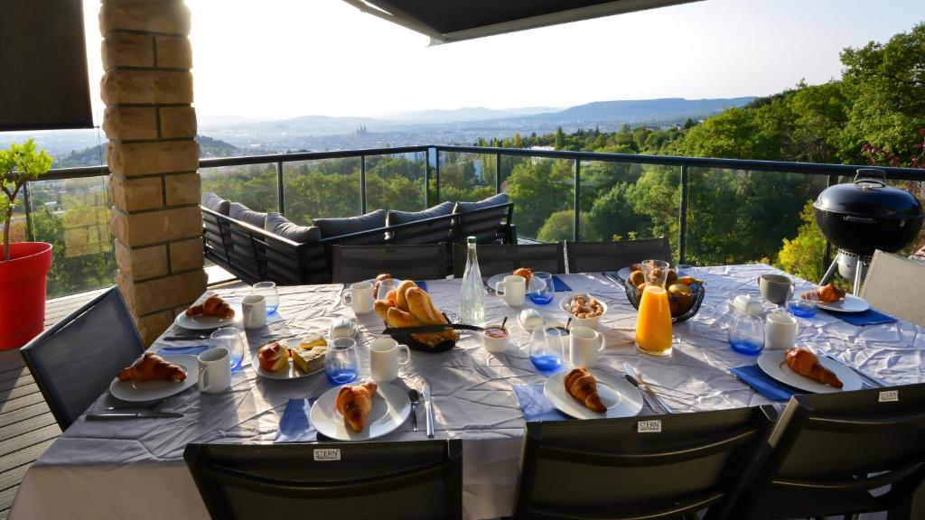 una mesa con platos de comida en la parte superior de un balcón en Chambres d'hôtes Villa Volcano en Durtol