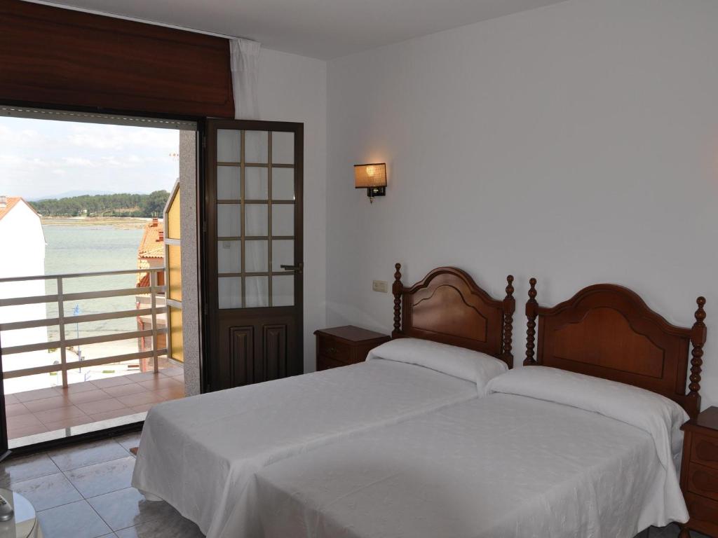 Dormitorio con cama y vistas al agua en Hostal Mourelos, en O Grove