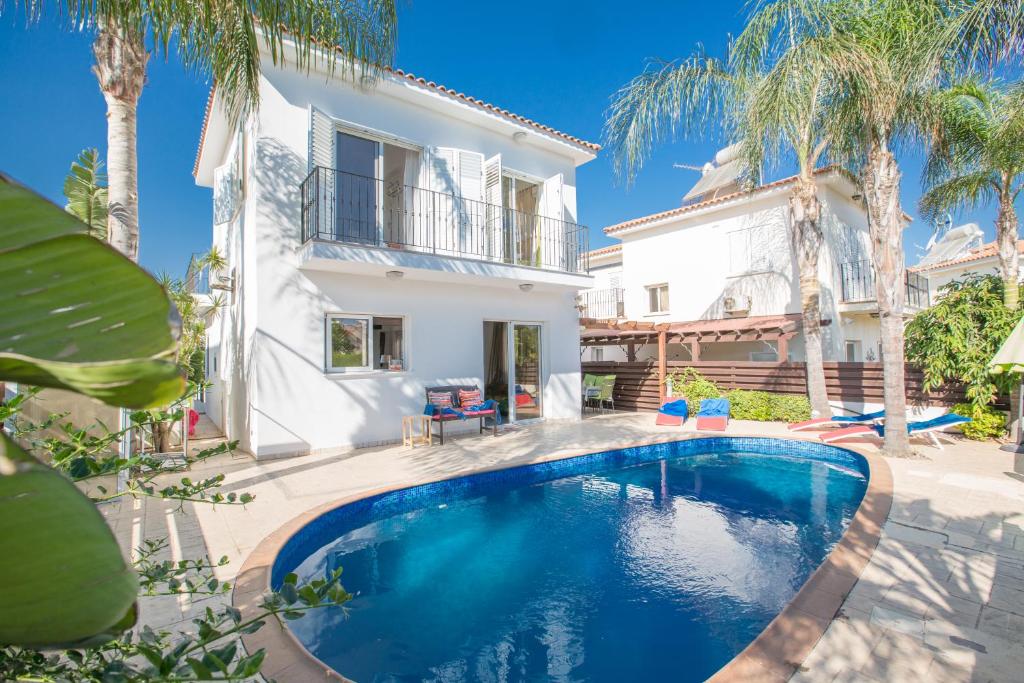 uma piscina em frente a uma casa com palmeiras em Villa Papantonia em Protaras