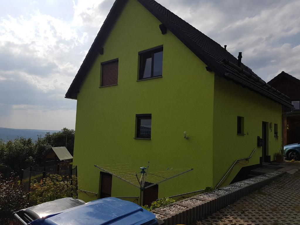 ein grünes Haus mit einem davor geparkt in der Unterkunft Ferienwohnung S. Armbruster in Bernsbach