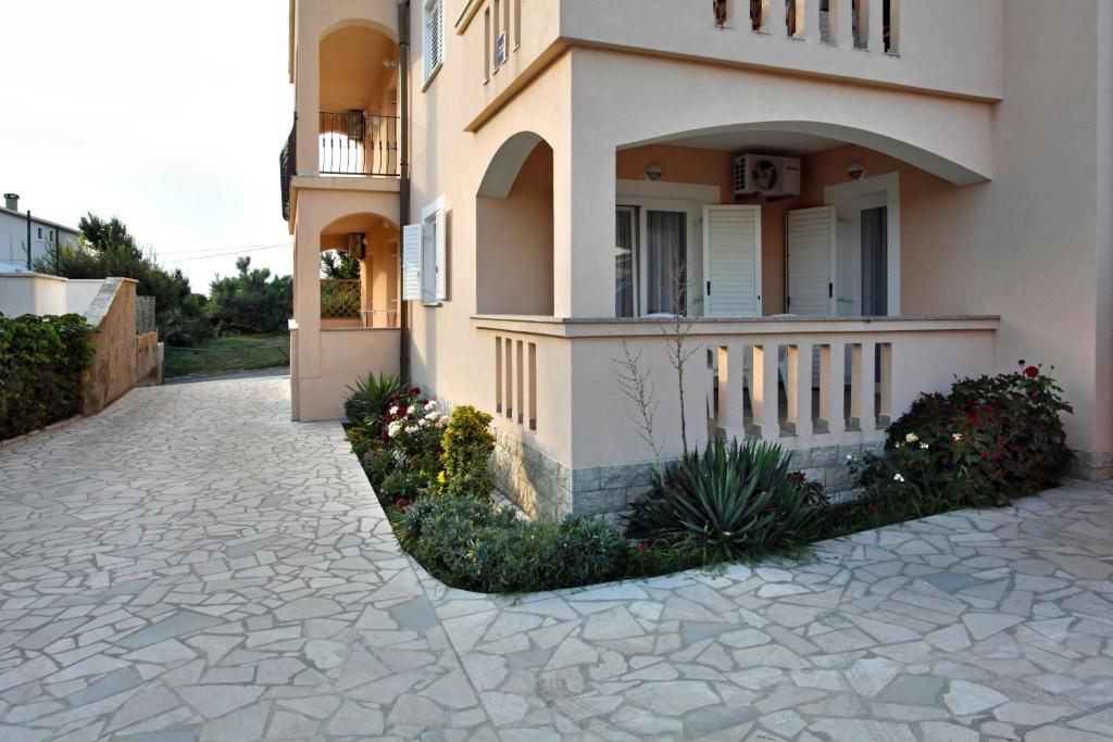 a house with a stone driveway in front of it at Apartmani Radan in Pag
