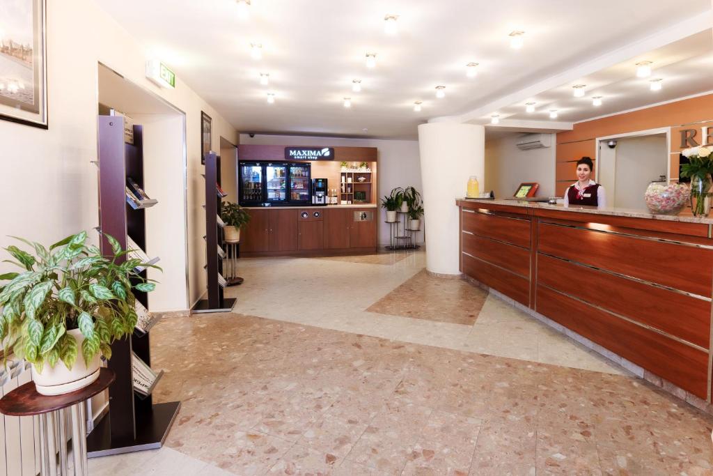 a woman standing at a reception desk in a lobby at Maxima Slavia Hotel in Moscow