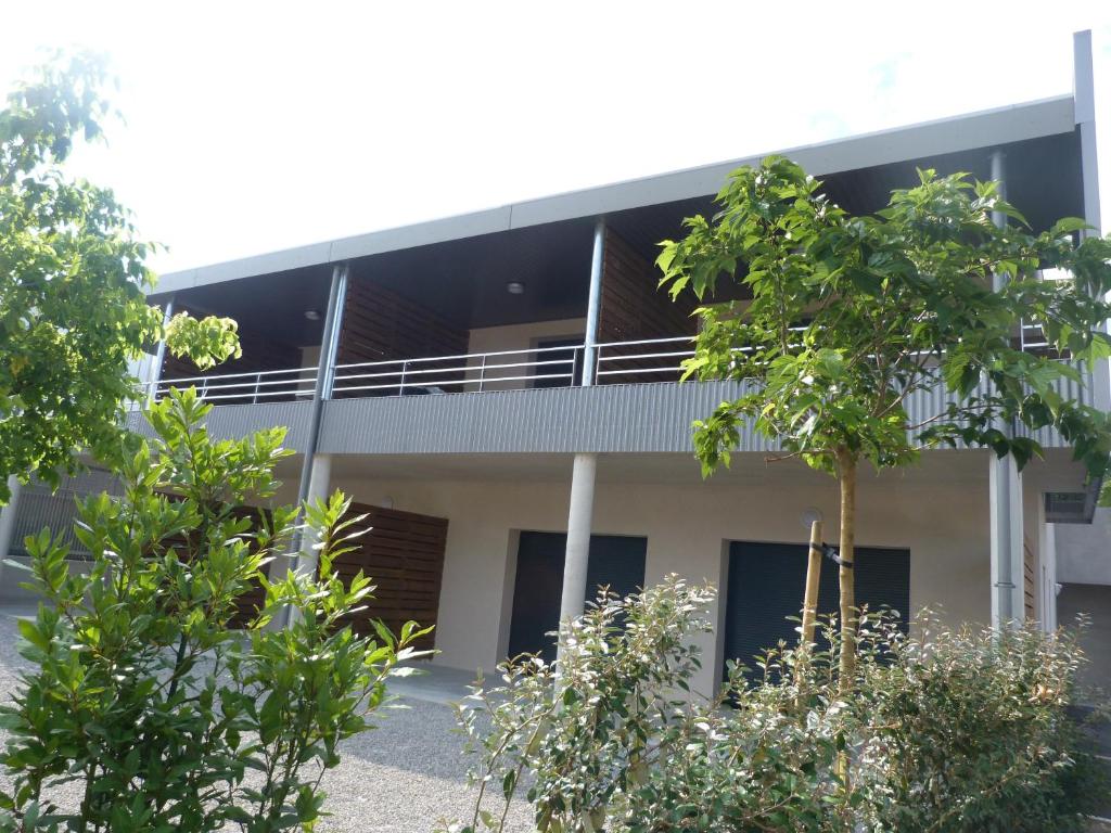 une vue extérieure d'un bâtiment avec des arbres au premier plan dans l'établissement Résidence Le 101, à Millau