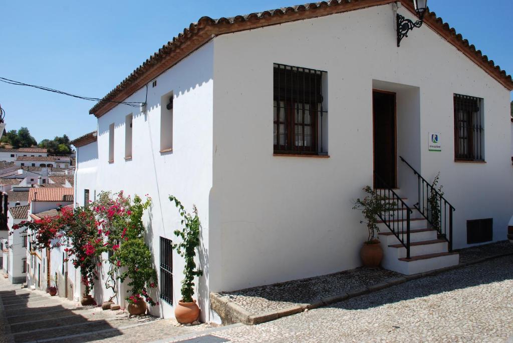 a white building with stairs and flowers on the side at Casa Rural La Torre in Almonaster la Real