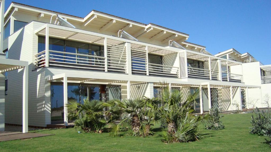 ein weißes Haus mit Palmen davor in der Unterkunft Troia Residence by The Editory - Beach Houses in Troia