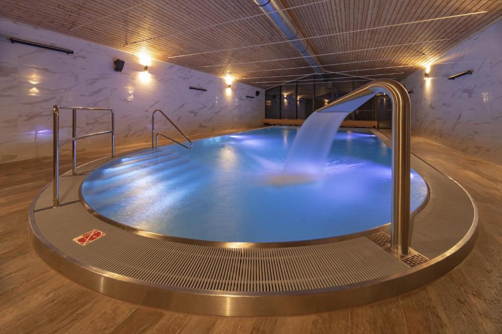 a swimming pool with a large glass tub at Wellness Hotel Astra in Špindlerův Mlýn
