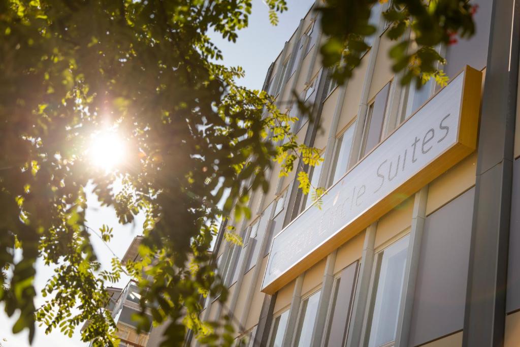 a building with the sun shining through a tree at Hotel Golden Circle Suites in Rovaniemi