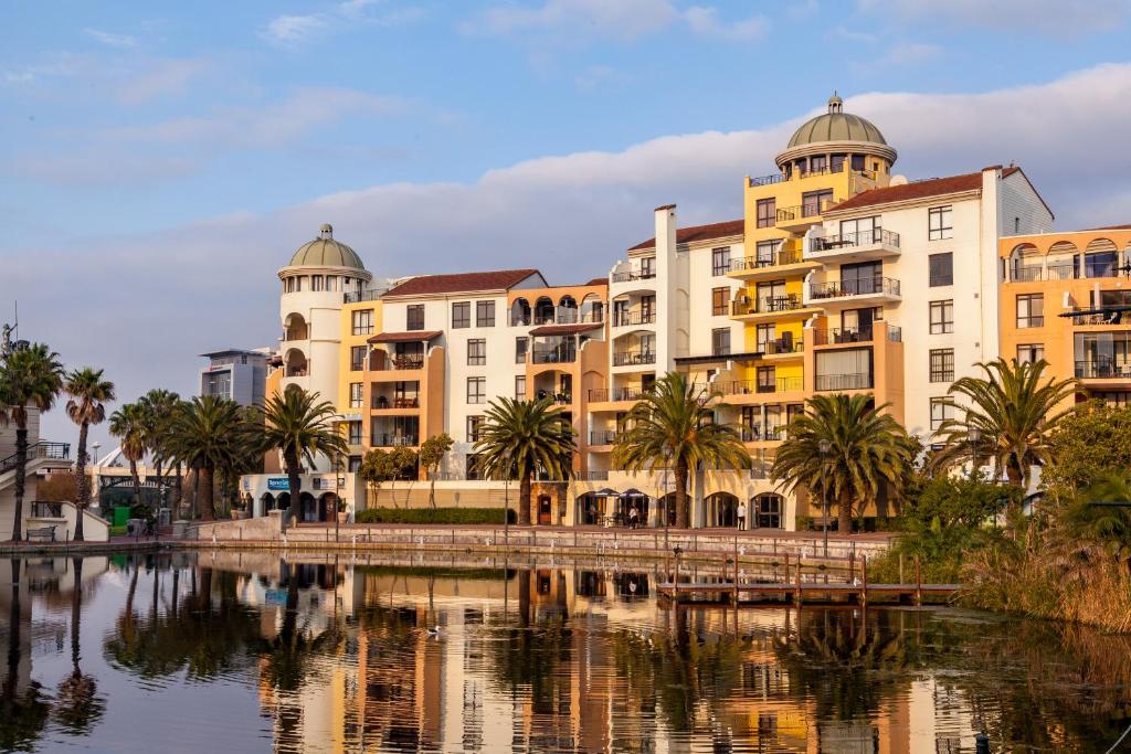 um grupo de edifícios ao lado de uma massa de água em Island Club Hotel & Apartments na Cidade do Cabo