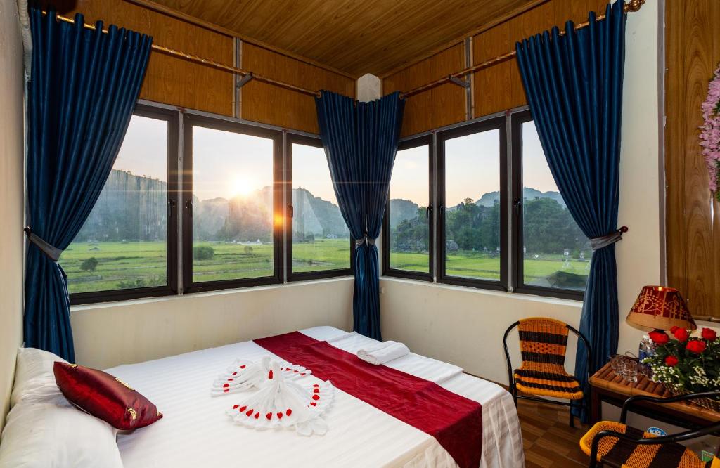 sypialnia z łóżkiem z niebieskimi zasłonami i oknami w obiekcie Hang Mua Central Homestay w mieście Ninh Binh