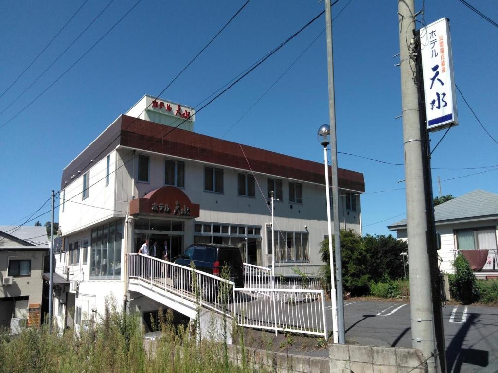 um edifício branco com um sinal em frente em Hotel Tensui em Misawa