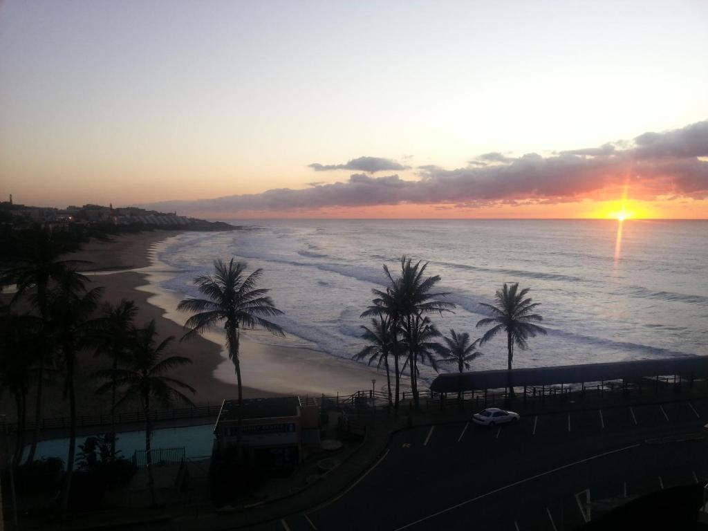 una puesta de sol sobre una playa con palmeras y el océano en Seabrook In-house Holiday Rentals en Margate