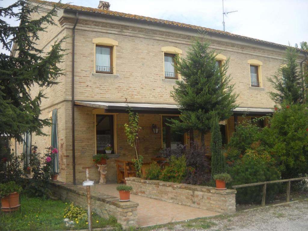 a large brick house with a garden in front of it at Al Casolare in Corinaldo