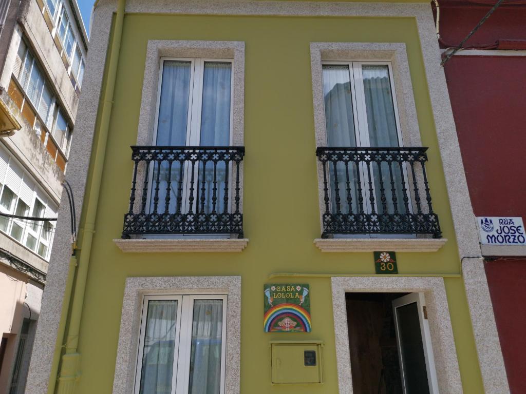 a yellow house with black balconies on a street at Casa Lolola in Sada