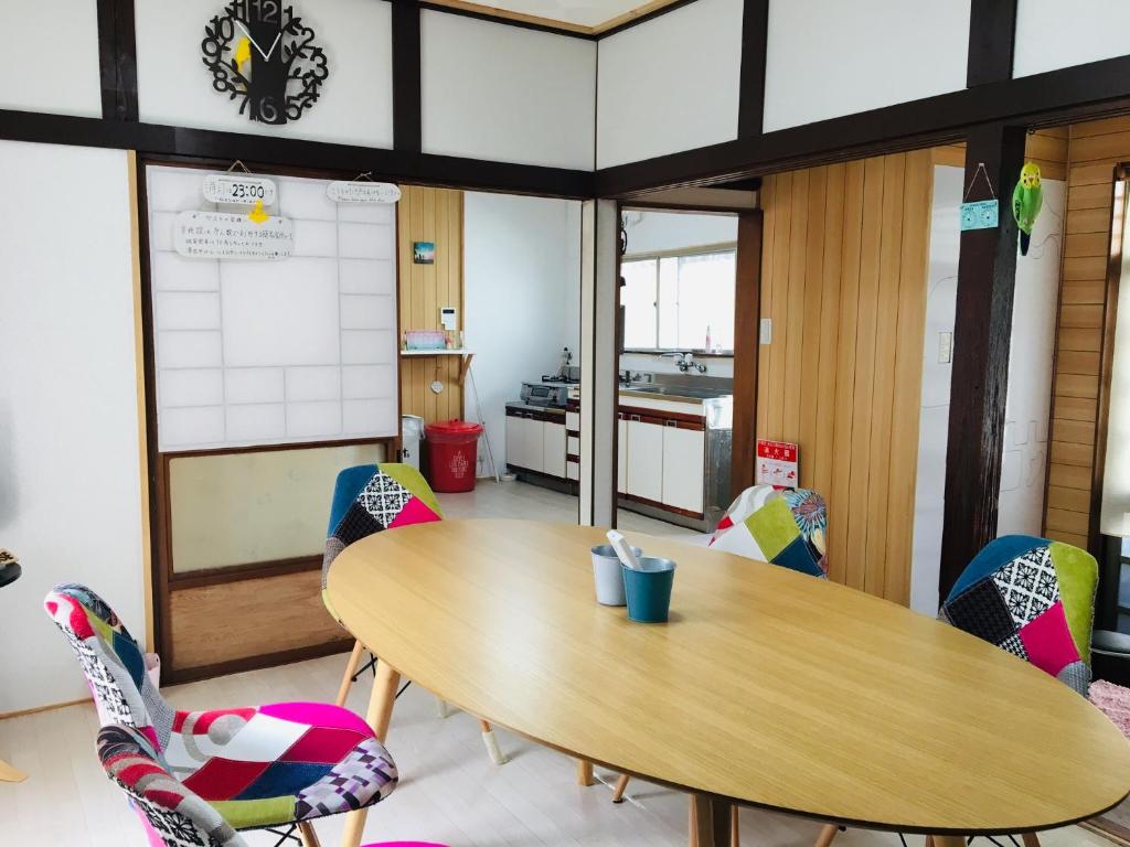 a classroom with a wooden table and chairs at Guesthouse Perche Female Only in Amami