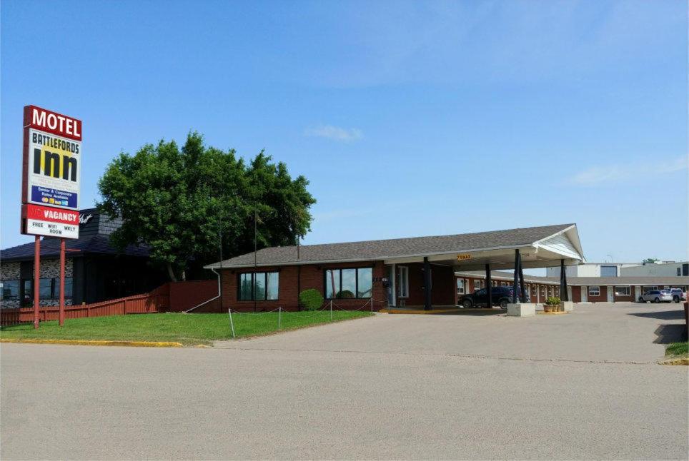 un motel con un cartel frente a un edificio en Battlefords Inn, en North Battleford