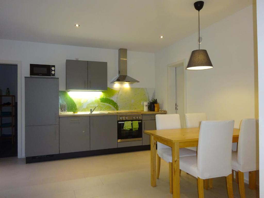 cocina con mesa de madera y sillas blancas en 2-Zimmer-Ferienwohnung im Herzen von Nordkirchen, en Nordkirchen