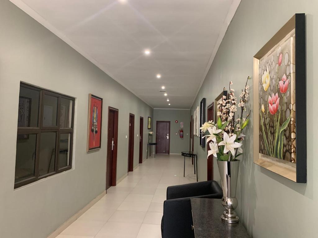 um corredor com um vaso de flores sobre uma mesa em Bannerloft Guest house em Gaborone