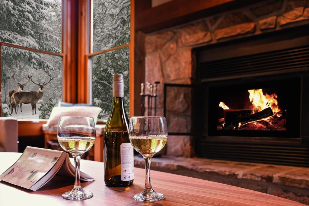 two glasses of white wine on a table with a fireplace at Chic log chalet with hot tub - Mont-Tremblant north side by Reserver.ca in Lac-Superieur