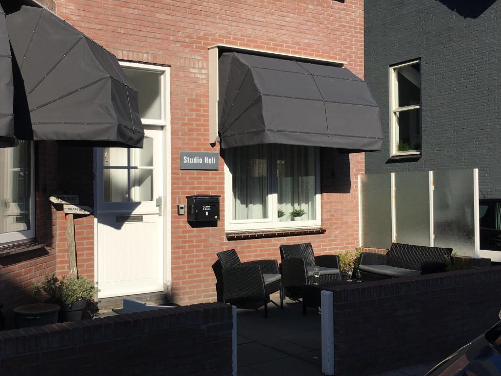 a patio with chairs and an umbrella in front of a building at Studio HeLi in Zandvoort