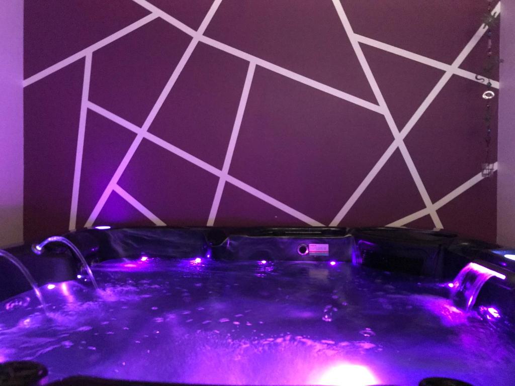 bañera púrpura con luces púrpuras en una habitación en Une Pause Douceur - Suite Orchidée, en Eyguières