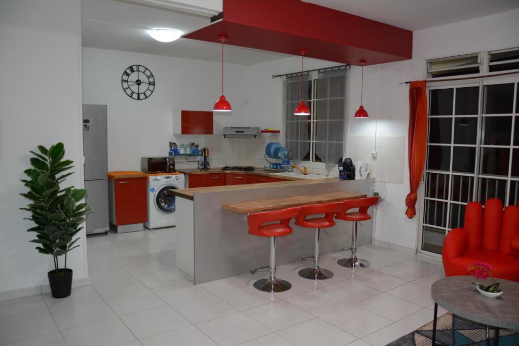 a kitchen with a counter and red stools in it at Bel appartement in Le Moule