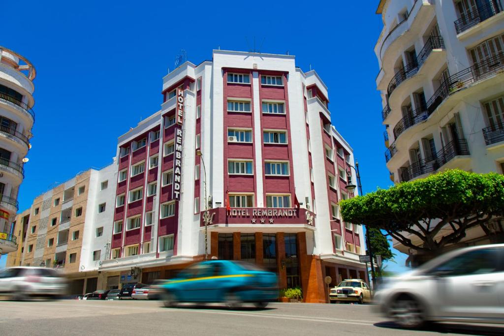 a red and white building on a city street with cars at Hôtel Rembrandt in Tangier